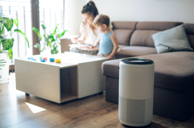 A family in the background of a living room with an air purifier in the foreground